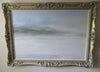 A figure sitting by a fire on the beach in a snowstorm